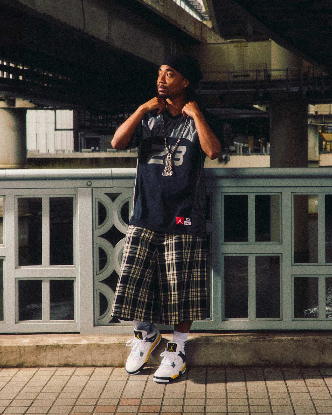 Man draagt de Air Jordan 4 Tour Yellow in een geruite short, campagnebeeld