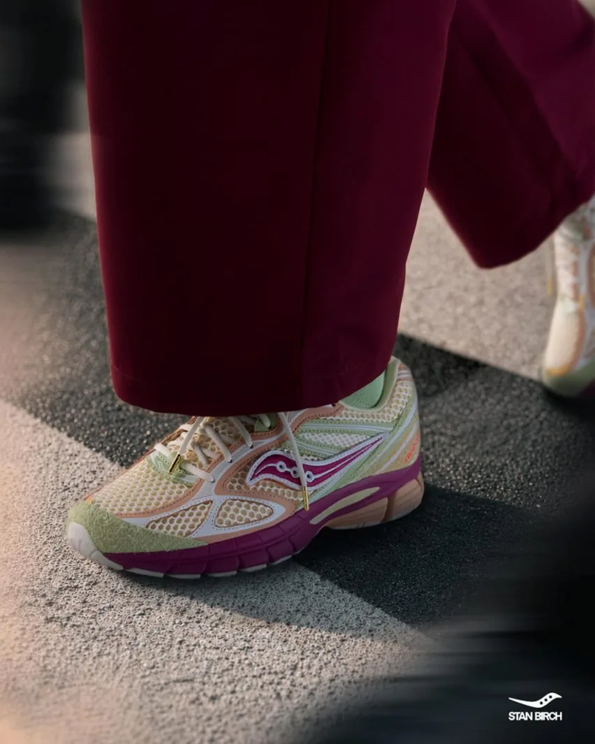 On-foot view of the Saucony x Stan Birch ProGrid Guide 7 worn with burgundy trousers on a crosswalk