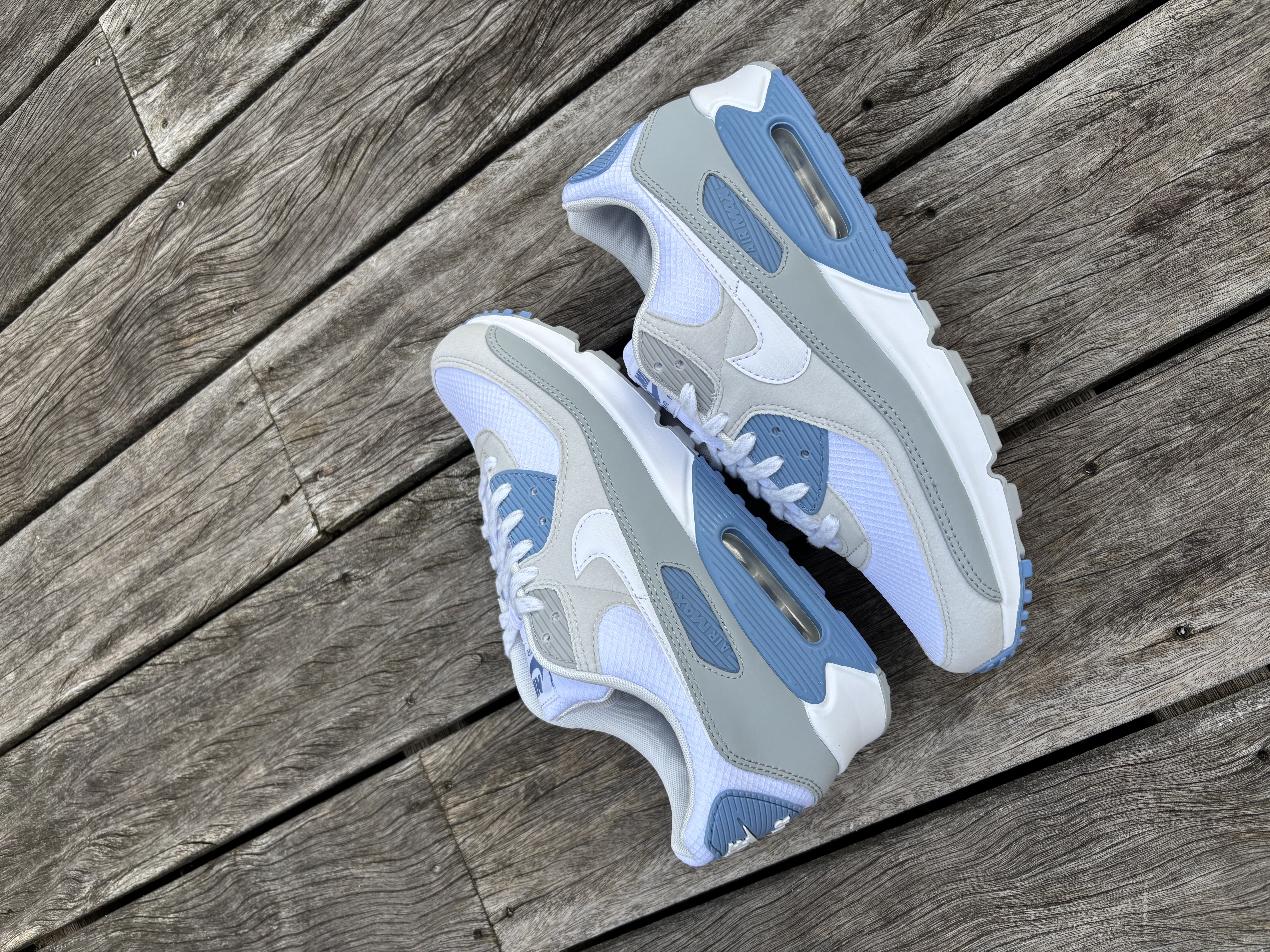 Nike Air Max 90 in wit, grijs en blauw – paar op houten vlonder