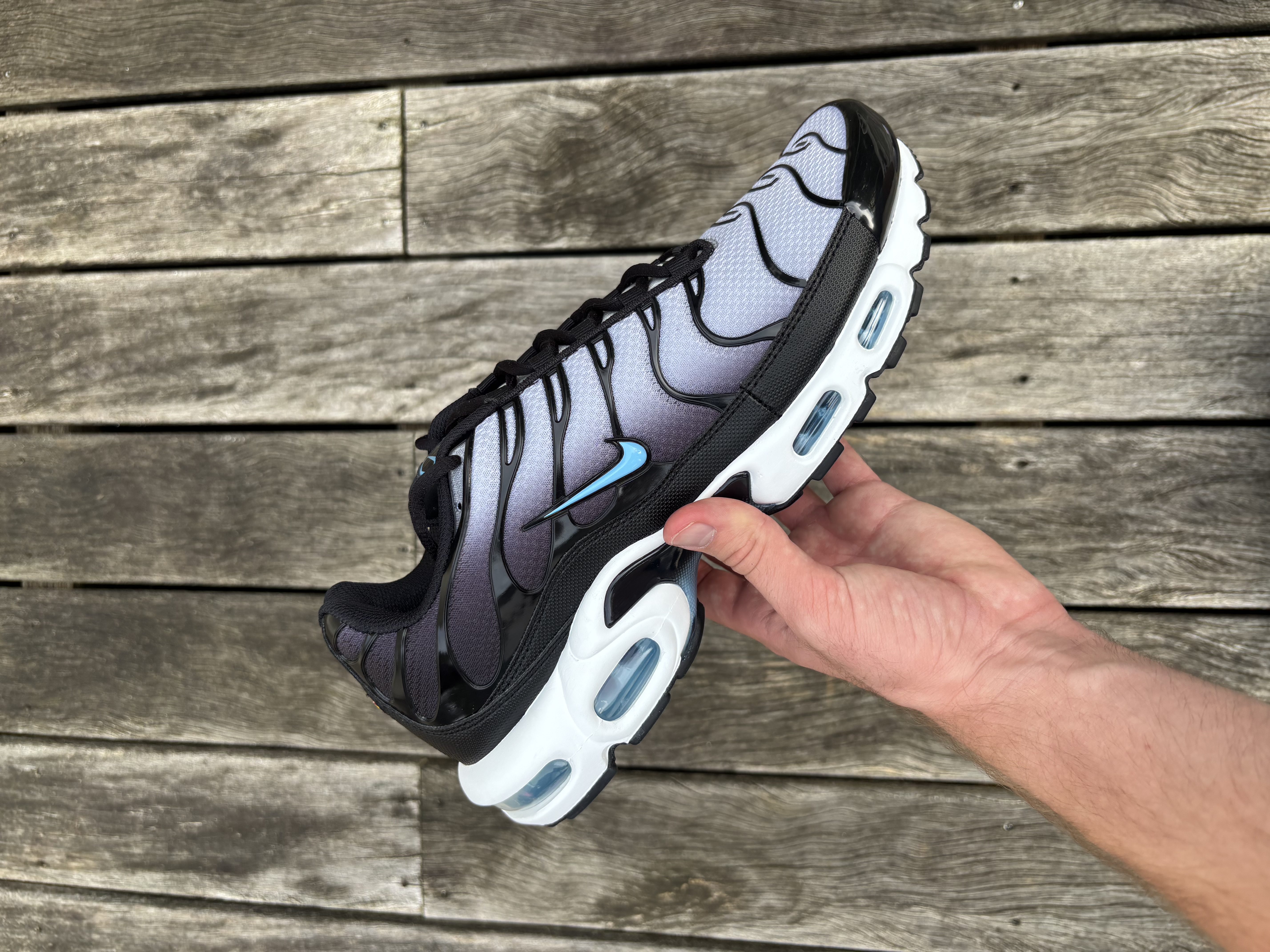 Nike Air Max Plus in zwart, grijs en Football Blue – in de hand