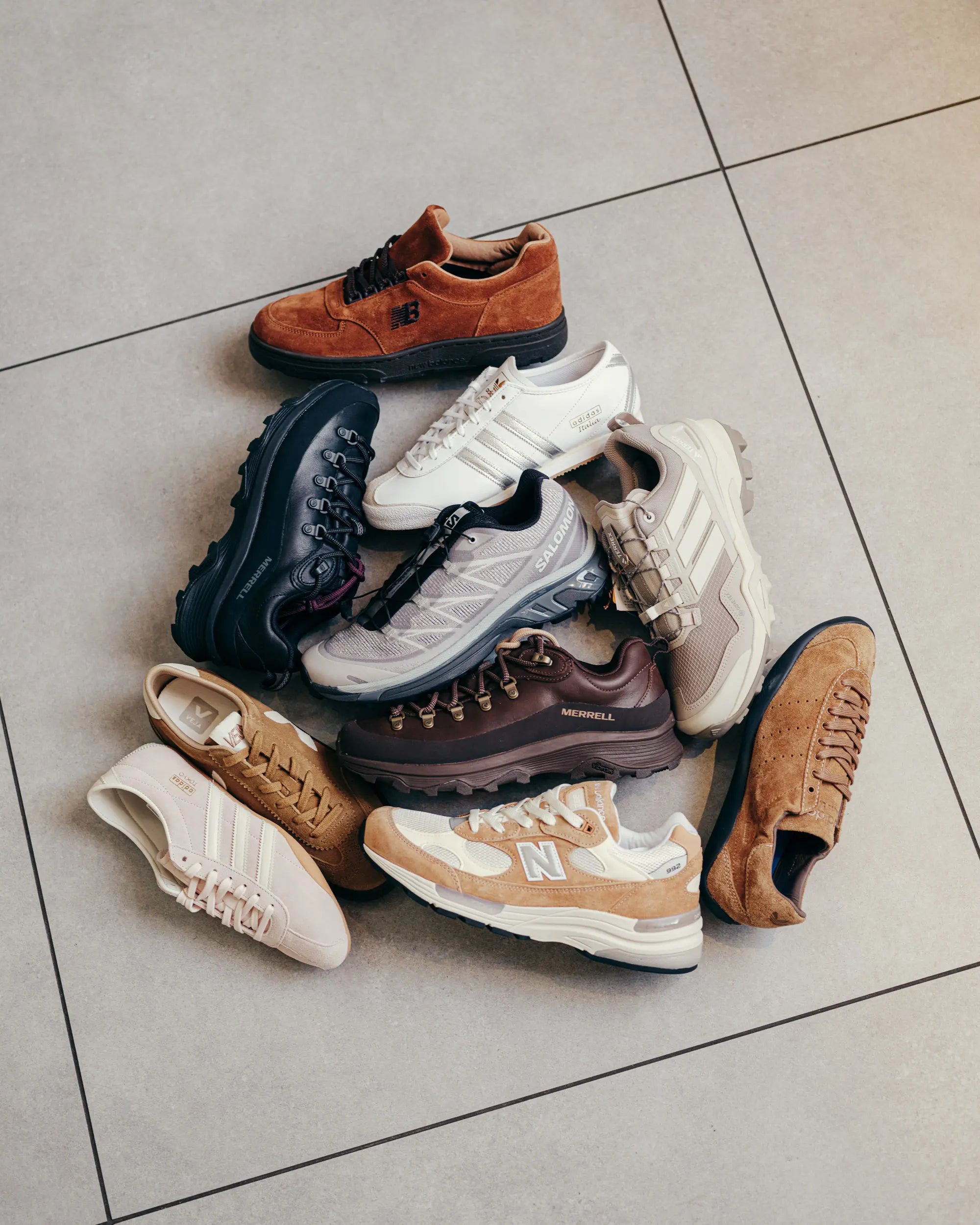 Sneaker in braunen, beigen und weißen Herbsttönen im Kreis auf einem Fliesenboden