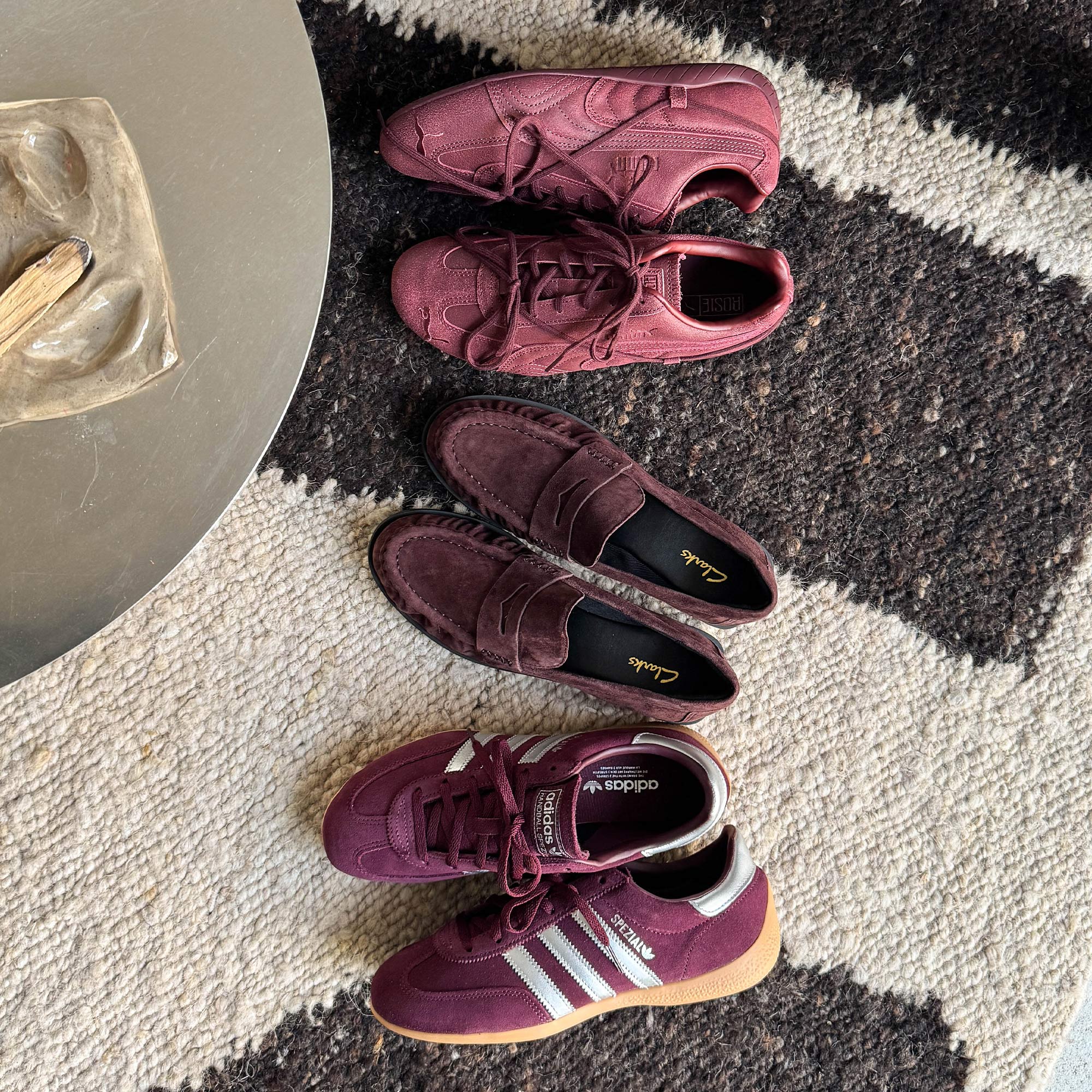 Mehrere bordeauxrote Wildleder-Sneaker auf einem schwarz-weißen Teppich