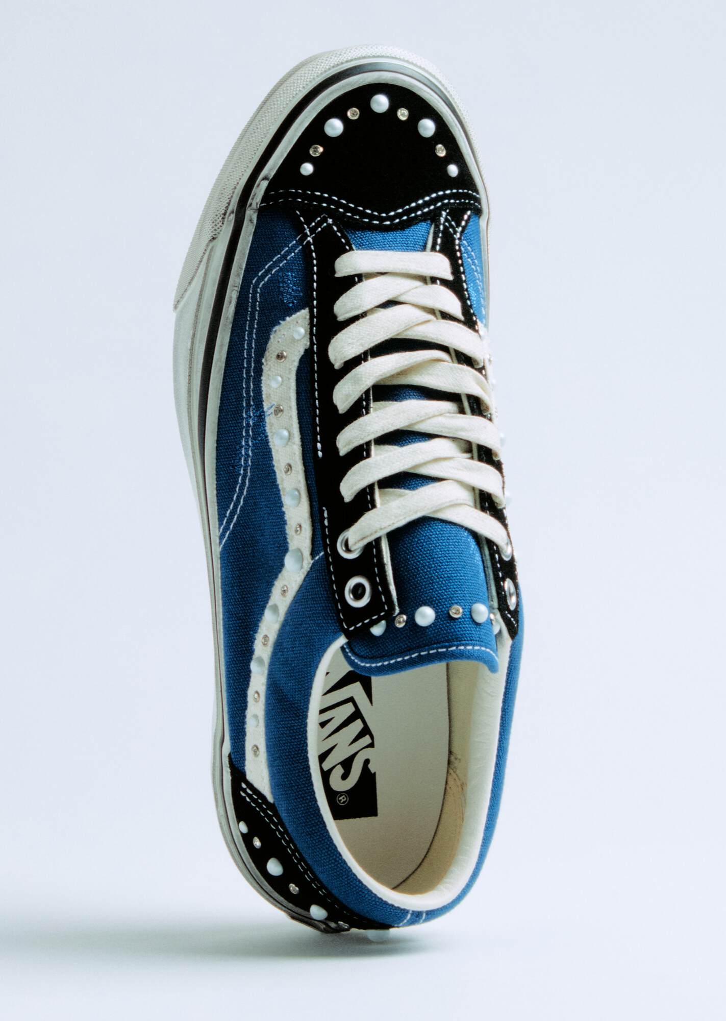 Drei gestapelte Vans Old Skool Sneaker mit perlenartigen Nieten in Blau, Braun und Schwarz