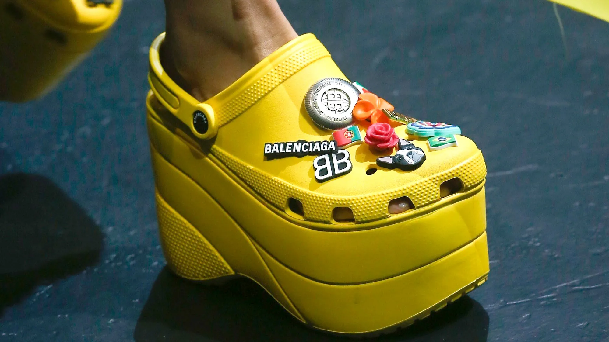 Balenciaga platform Crocs in bright yellow, featuring oversized sole and custom Jibbitz charms, high fashion Crocs collaboration.