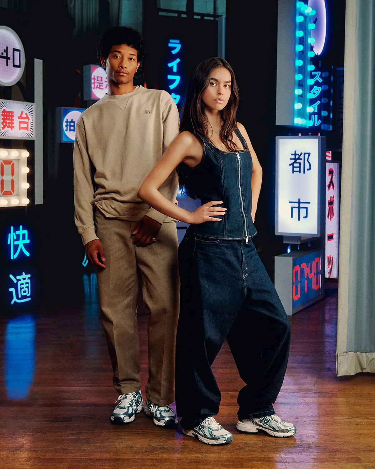man and woman wearing the New Balance 740 sneakers in the 'Marsh Green' and white colorway, with reflective silver overlays, styled in a modern urban setting